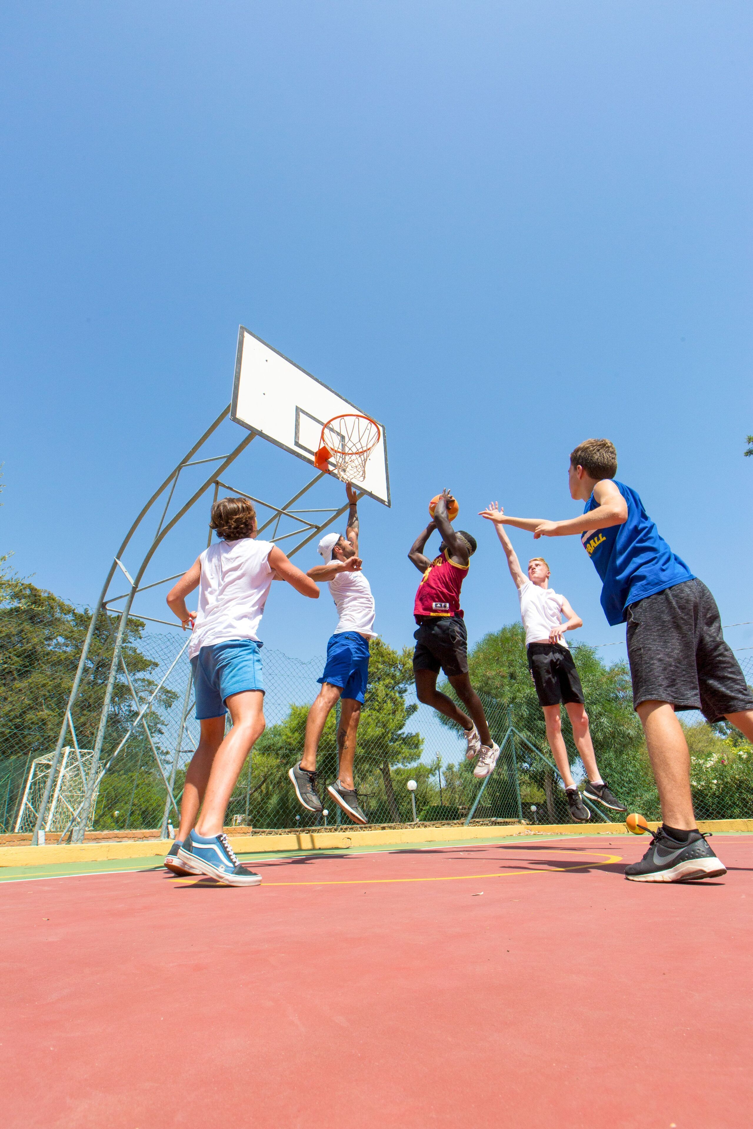 A group of people playing basketball on an outdoor court.