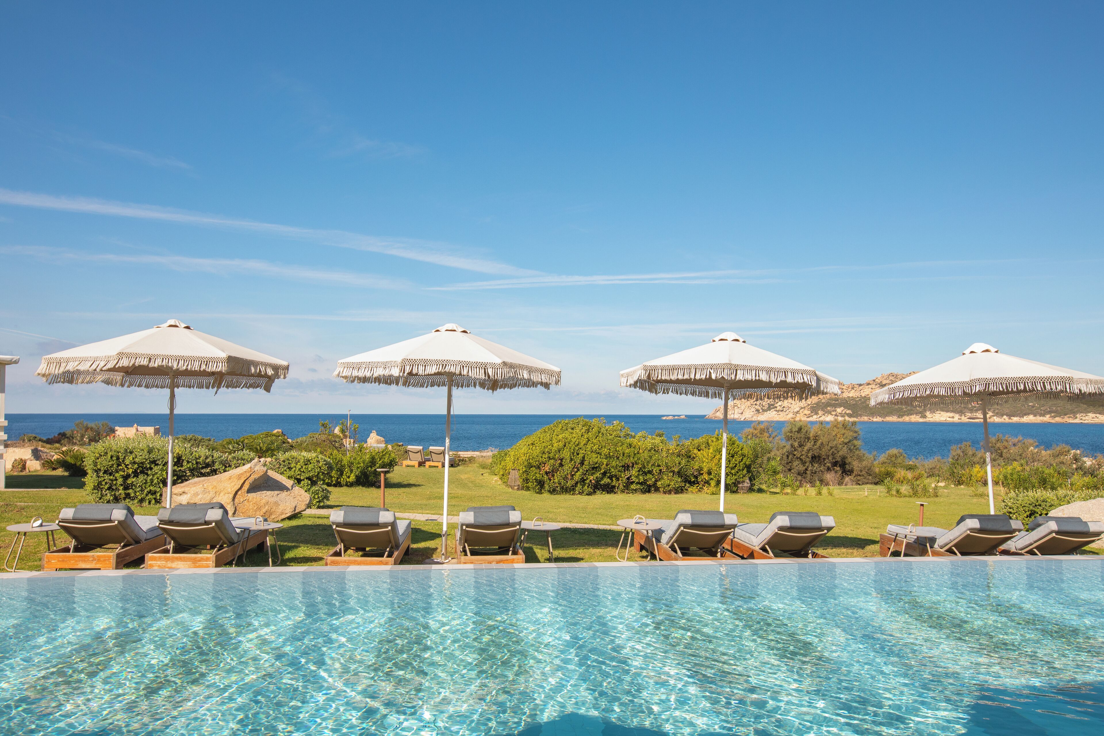 A poolside area with lounge chairs and umbrellas, overlooking a body of water.