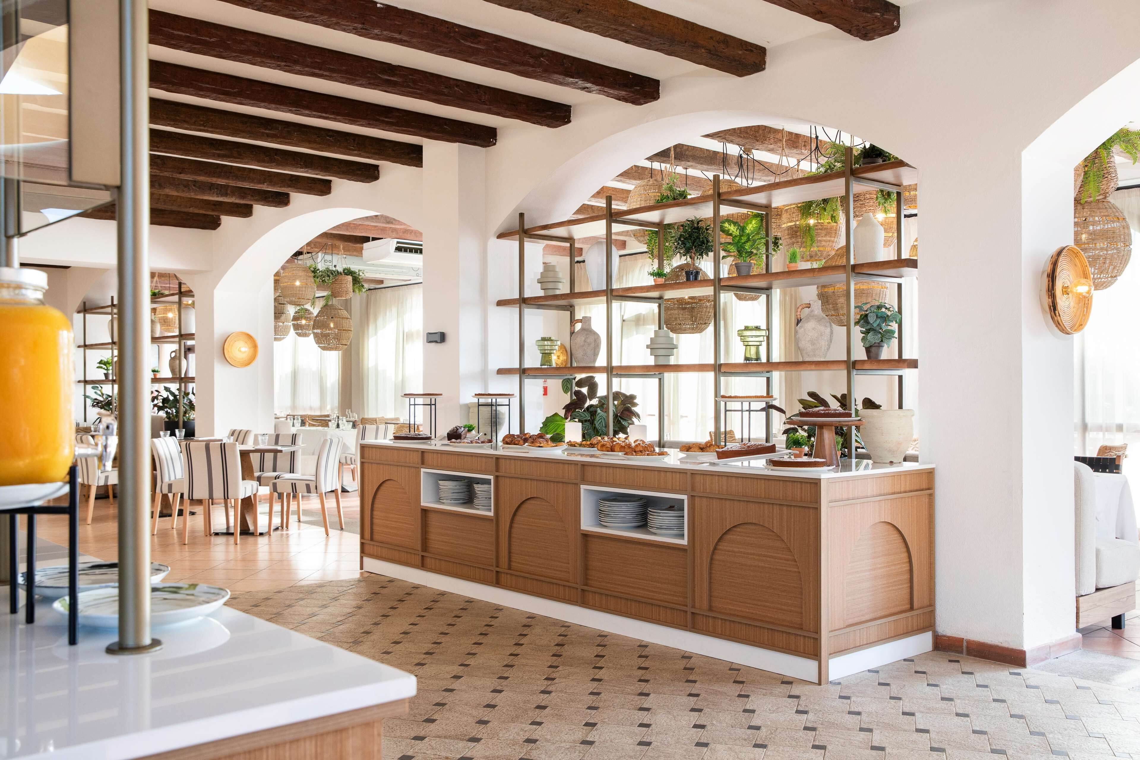 A spacious kitchen with wooden cabinets, a central island, and a hanging plant display.