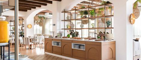 A spacious kitchen with wooden cabinets, a central island, and a hanging plant display.