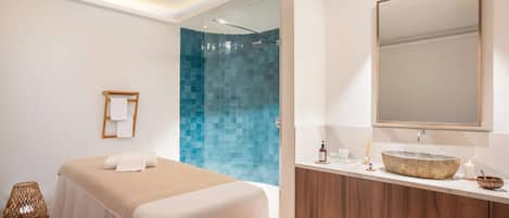 Un baño moderno con un espejo grande, un tocador de madera y una zona de ducha con azulejos azules.