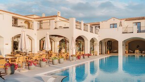 A poolside area with outdoor seating and potted plants. - Mangia's Santa Teresa Sardinia, Curio Collection by Hilton (Santa Teresa di Gallura)