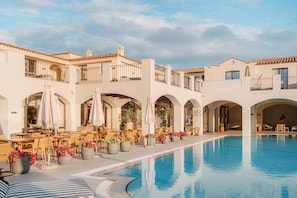 A poolside area with outdoor seating and potted plants. - Mangia's Santa Teresa Sardinia, Curio Collection by Hilton (Santa Teresa di Gallura)