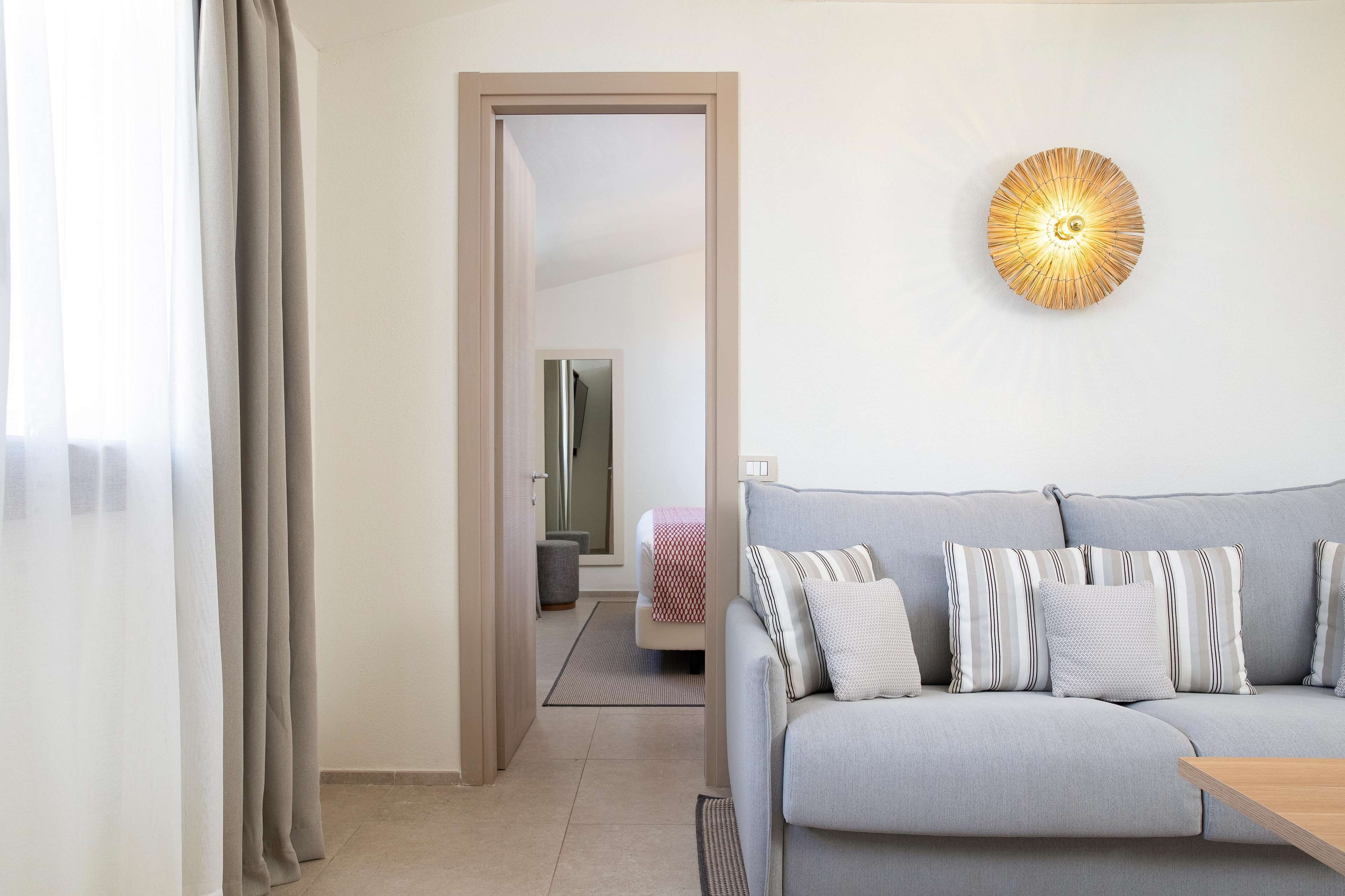 Una sala de estar moderna con un sofá gris, almohadones a rayas y una lámpara fijada a la pared.