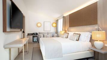Una habitación de hotel moderna con una cama grande, mesitas de noche, un televisor de pantalla plana y un minibar.
