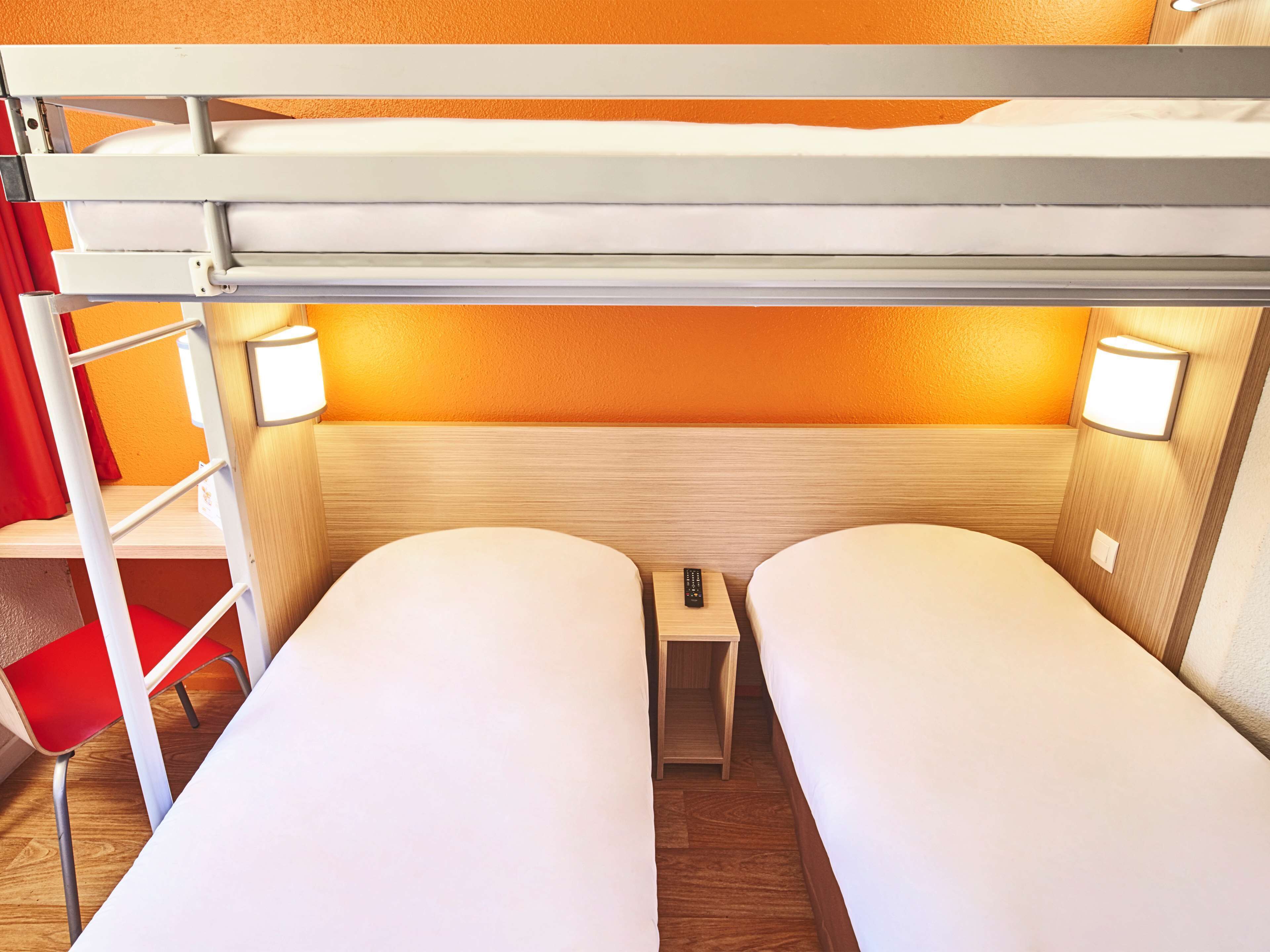 Habitación con literas, una mesita pequeña y una silla.