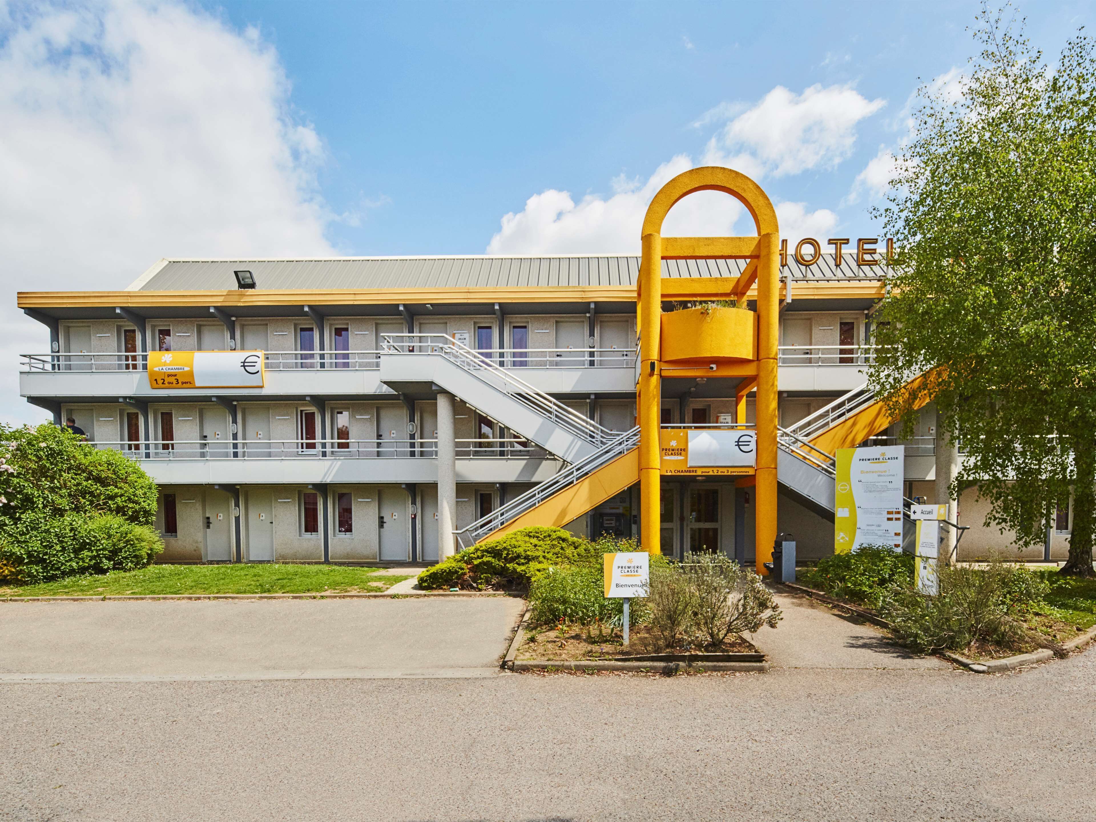 Un hotel con un ingresso giallo ben visibile, diversi balconi e un cielo sereno.