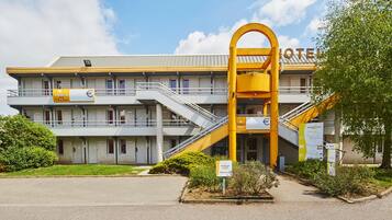 Un hotel con un ingresso giallo ben visibile, diversi balconi e un cielo sereno.
