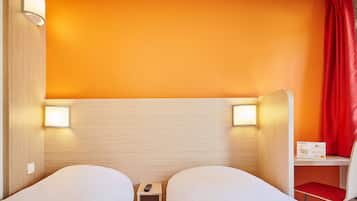 Une chambre d’hôtel avec deux lits, une petite table, une chaise et un rideau rouge.