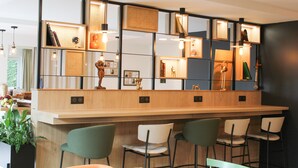 A modern bar area with a wooden counter, multiple chairs, and pendant lighting. - Hôtel Premiere Classe Melun Senart - Vert Saint Denis (Vert-Saint-Denis)