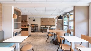 Un interior de cafetería moderno con mesas y sillas de madera, y una barra con utensilios de cocina.