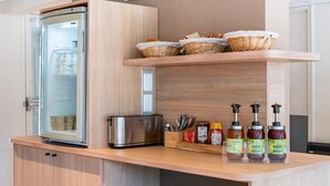 Una cocina con refrigerador, tostadora, cestas de mimbre y dispensadores de condimentos.