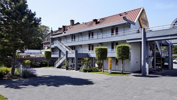 Un hotel con fachada moderna, varios balcones y una escalera central.