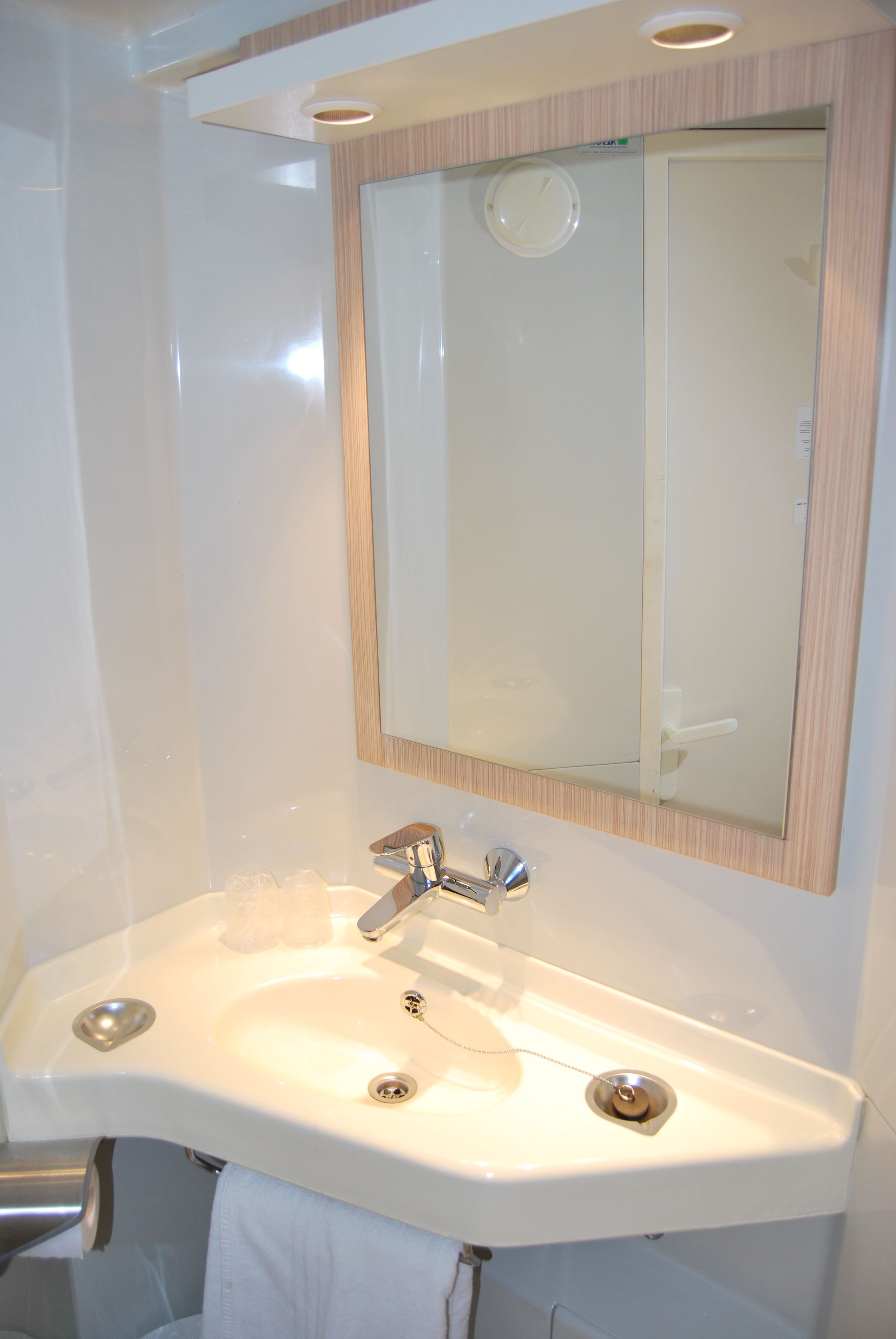 A bathroom with a white sink, a mirror, and a towel rack.