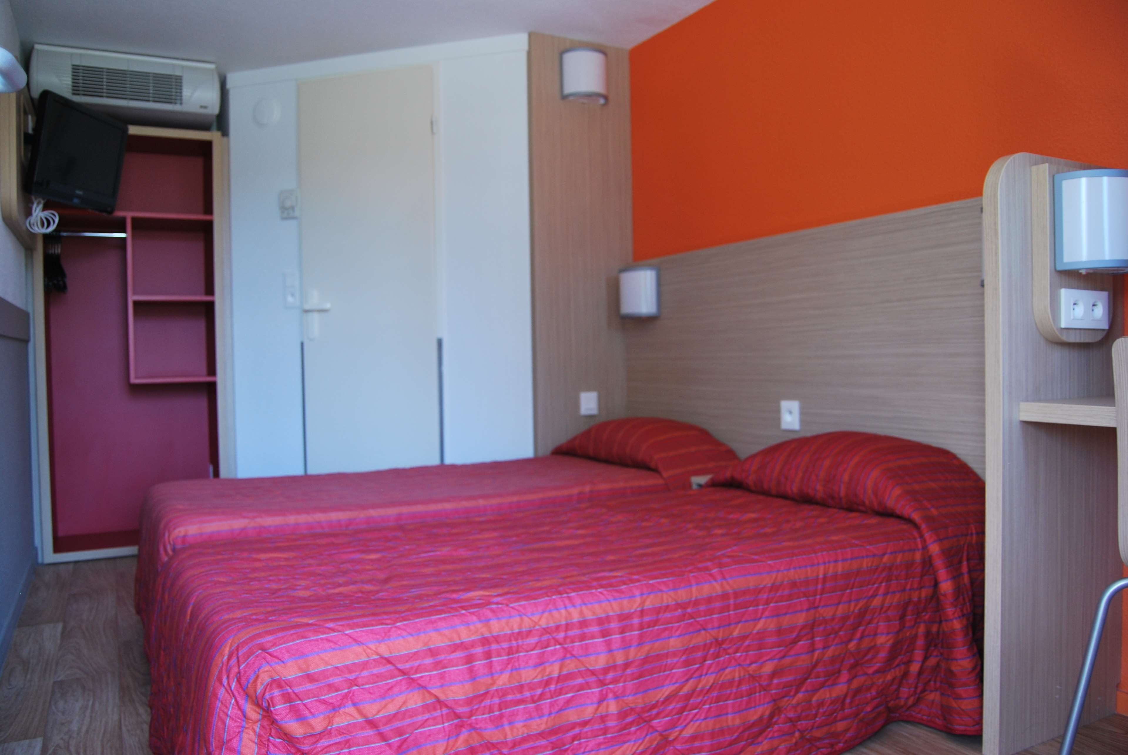 Een slaapkamer met een bed, een garderobe, een televisie en een wandlamp.