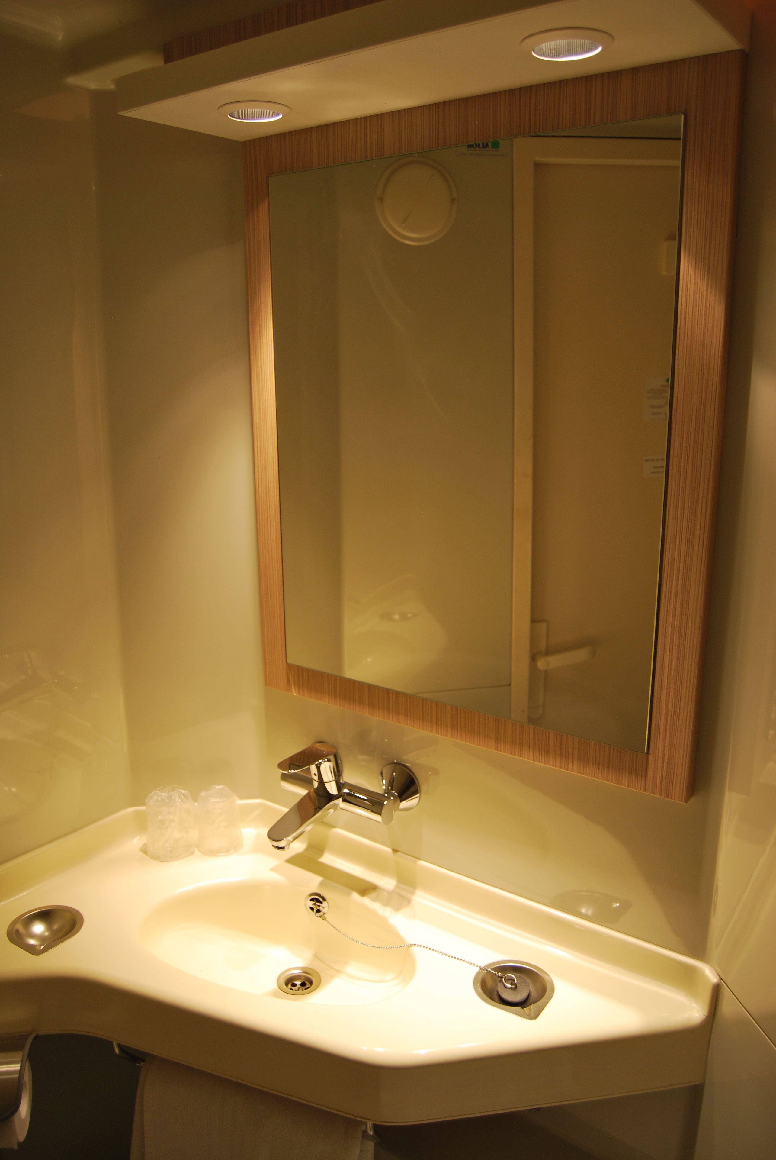 A bathroom with a white sink, a mirror, and a wooden frame.
