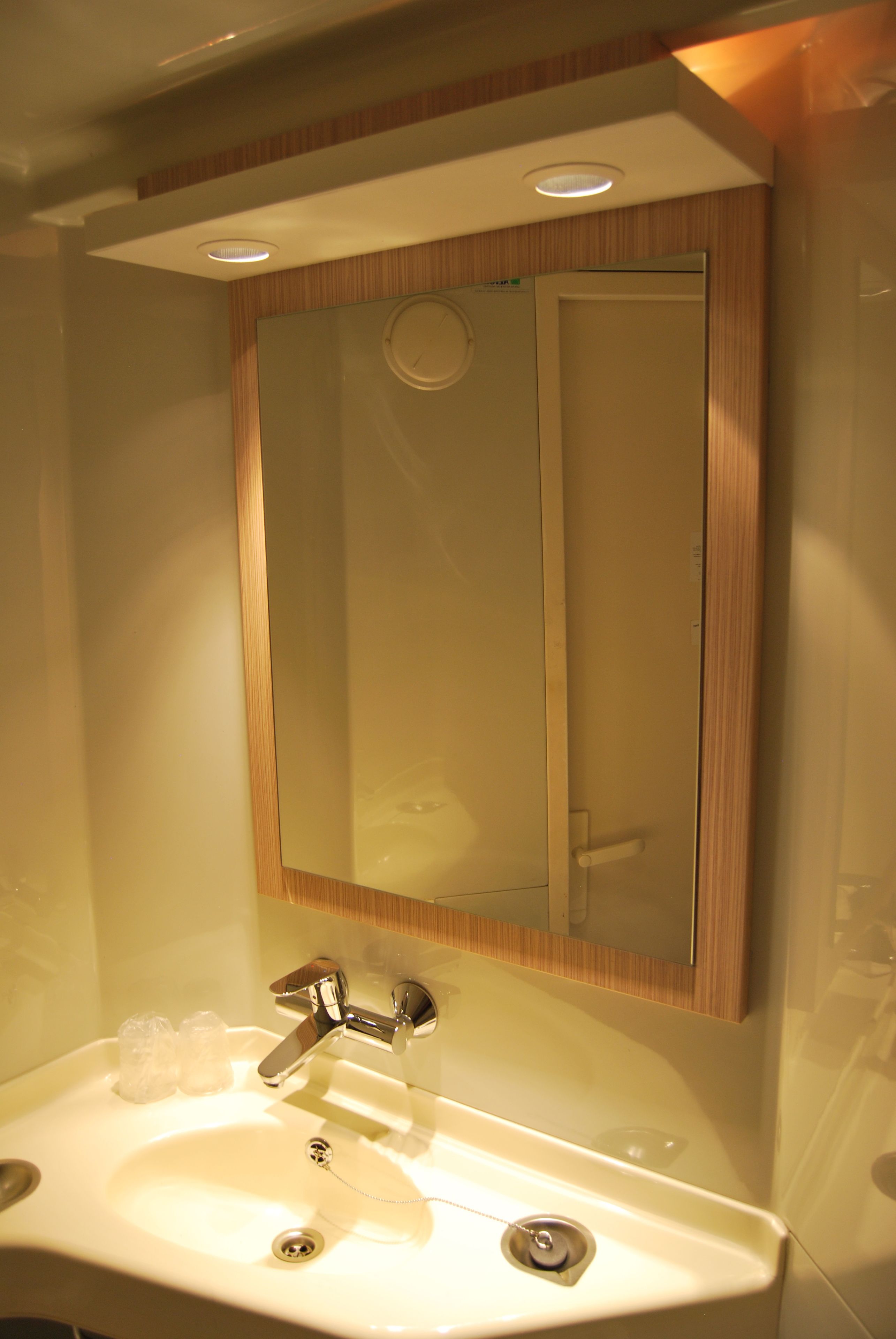 A bathroom with a sink, mirror, and wooden paneling.