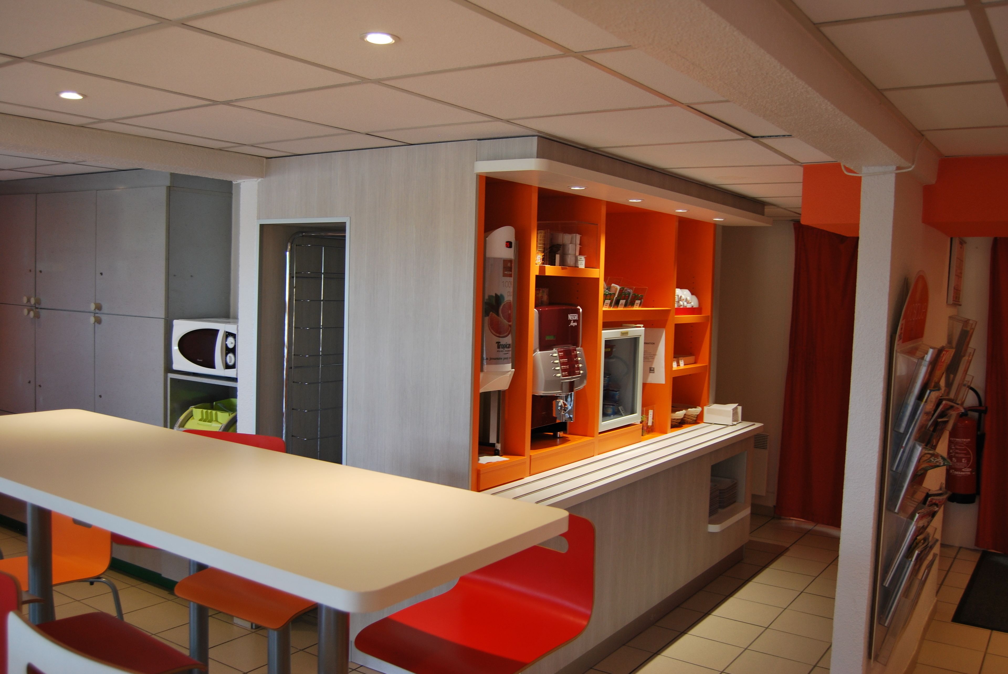 A modern kitchen with a long counter, orange and white cabinets, and a microwave.