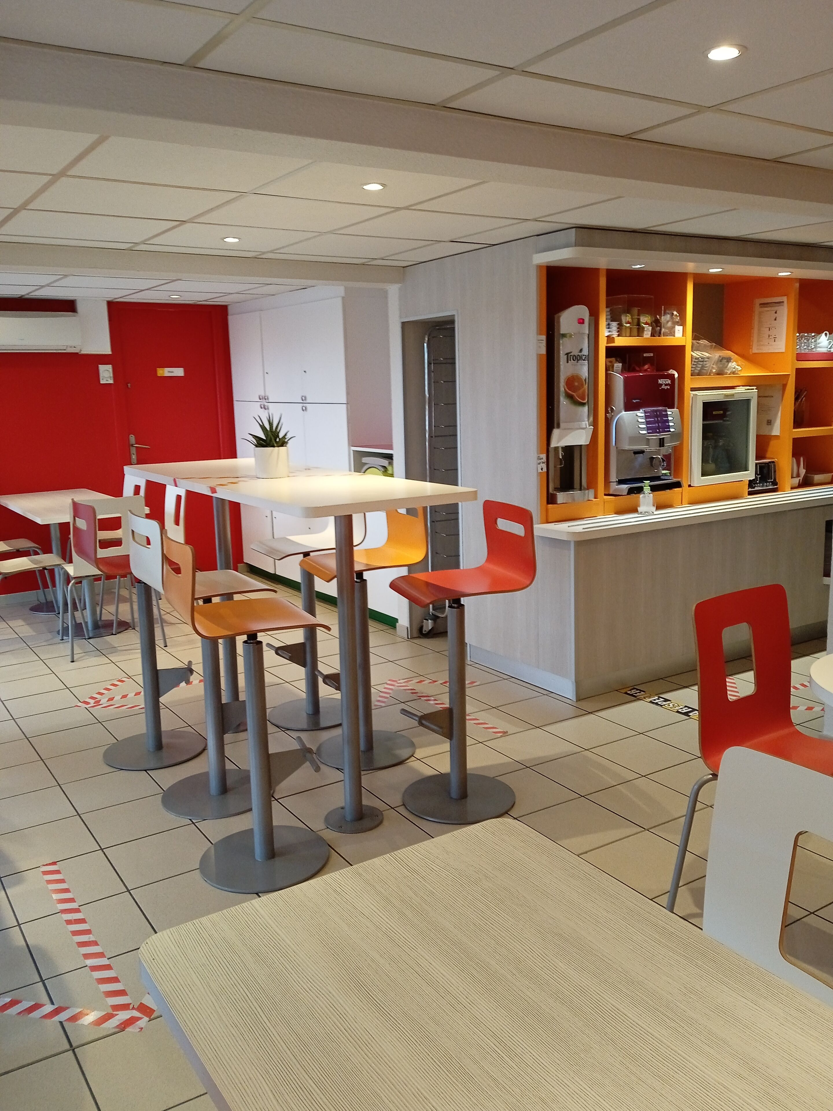Una cafetería moderna con una decoración en rojo y blanco, que presenta un mostrador con una máquina de café y un tablero de menú.
