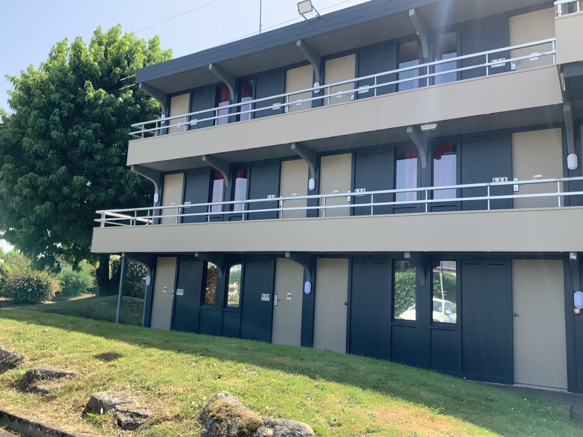 A two-story building with a flat roof, multiple windows, and a balcony on the upper floor.