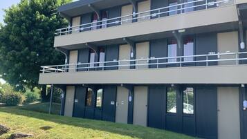 A two-story building with a flat roof, multiple windows, and a balcony on the upper floor.