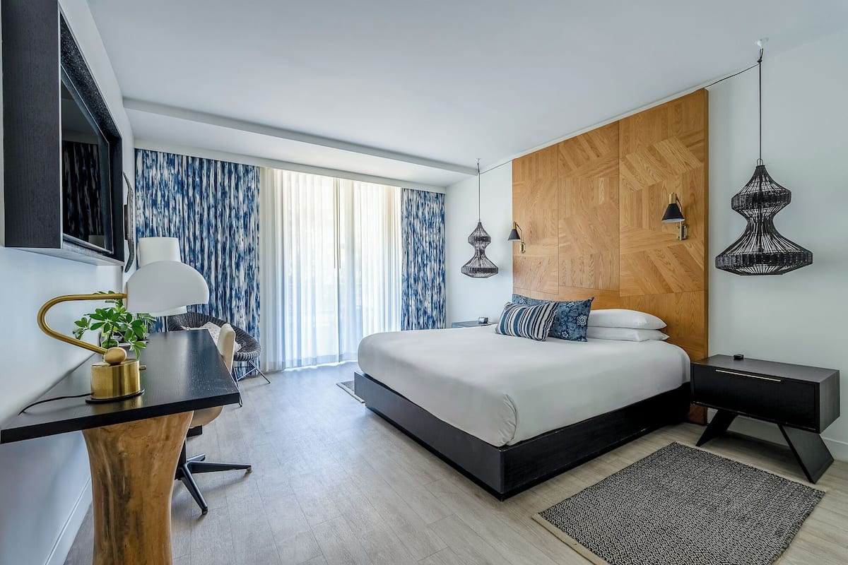 A modern bedroom with a bed, bedside tables, a desk, and a chair.