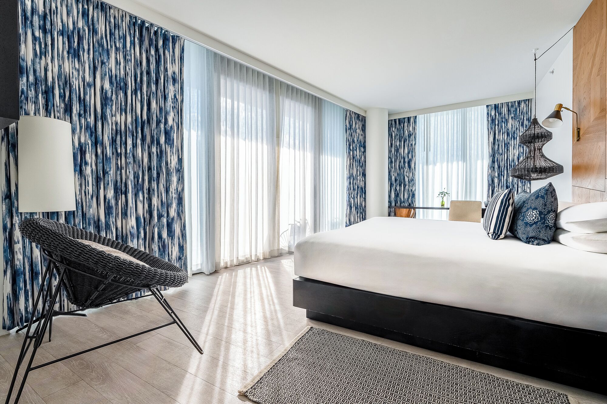 Une chambre d’hôtel moderne avec un grand lit, une chaise, un bureau et une lampe.