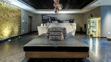 Eine Lobby mit einer Rezeption, einer gemusterten Couch, einer Kristallleuchtre und einer Glastheke.