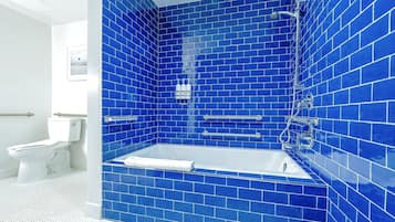 A bathroom with a white toilet, a white bathtub, and blue-tiled walls.