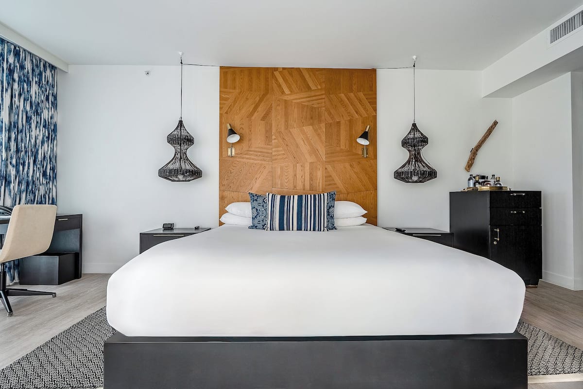 A modern bedroom with a large bed, two bedside tables, a desk, and a wardrobe.