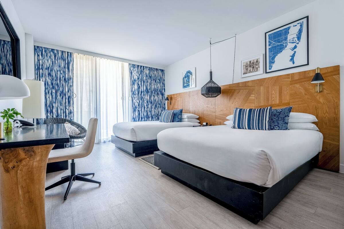 A modern hotel room with a large bed, a desk with a chair, and a view of the cityscape.