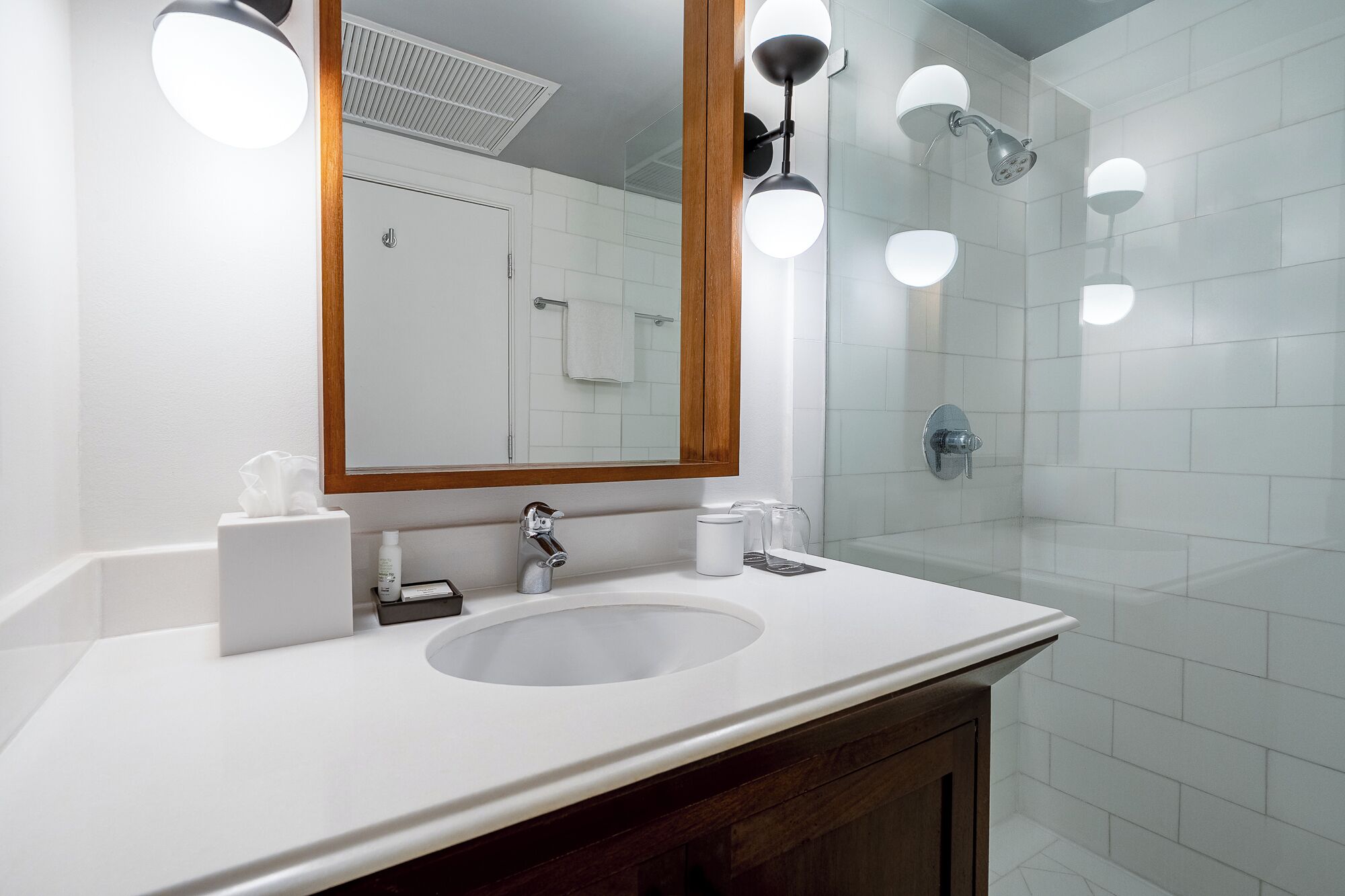A bathroom with a white sink, a mirror, and a glass shower enclosure.