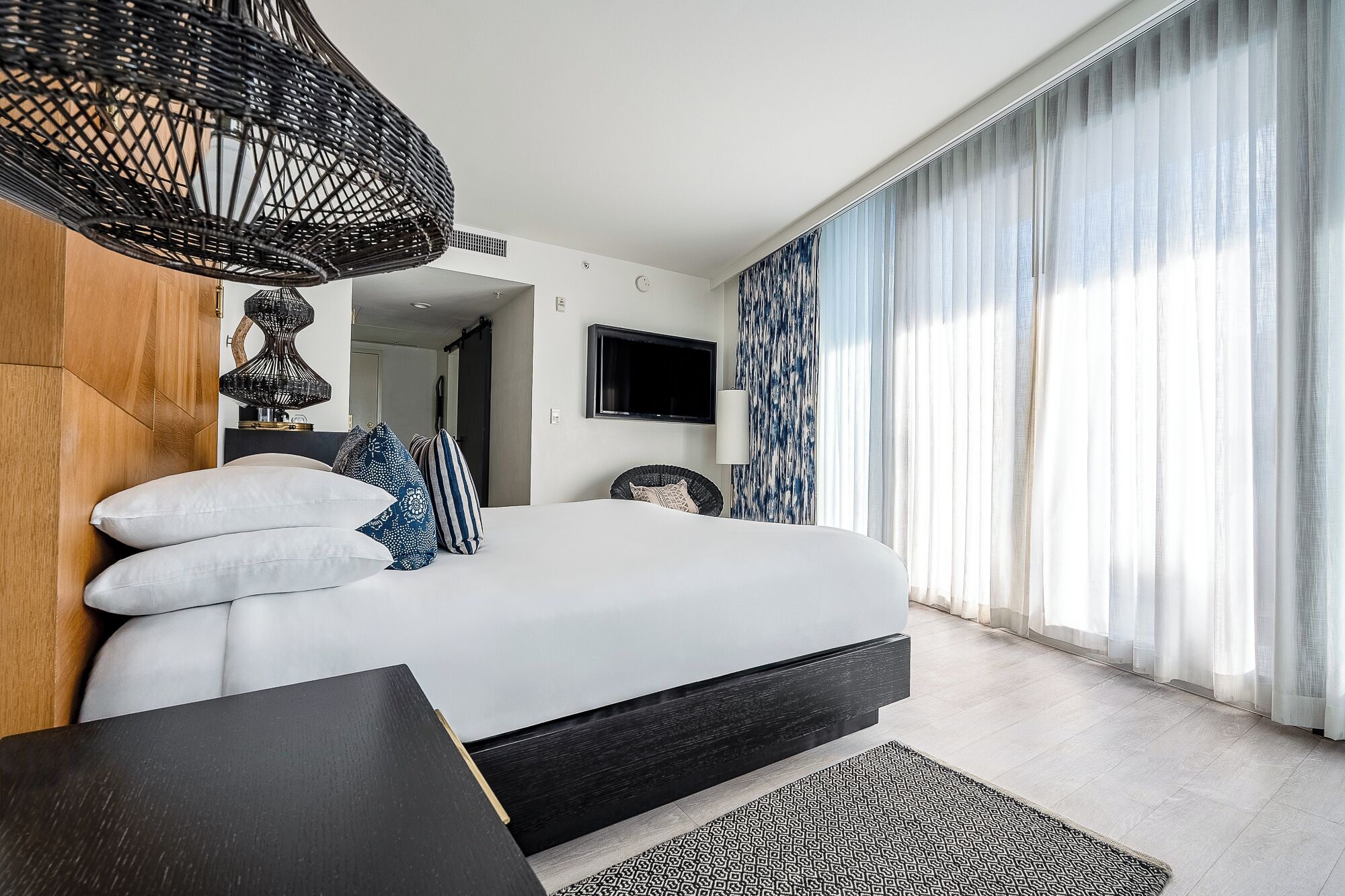 Una camera da letto moderna con un letto, una televisione e un'ampia finestra con tende.