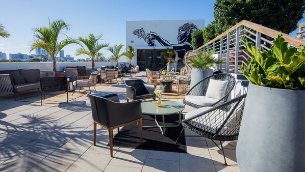 An outdoor patio with wicker furniture, a round table, and potted plants.