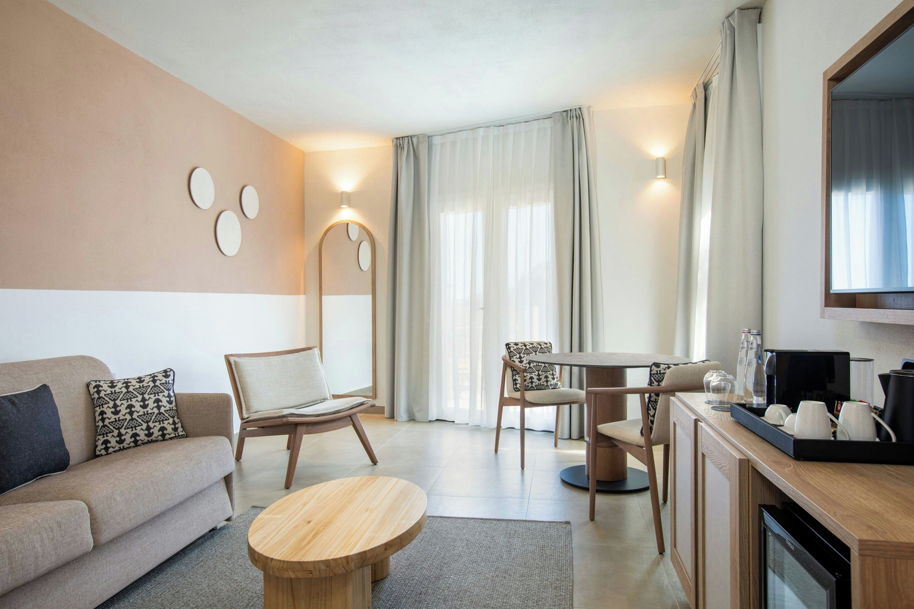 Ein modernes Wohnzimmer mit einer Couch, Sesseln, einem Couchtisch, einem Esstisch und einem Fernseher.