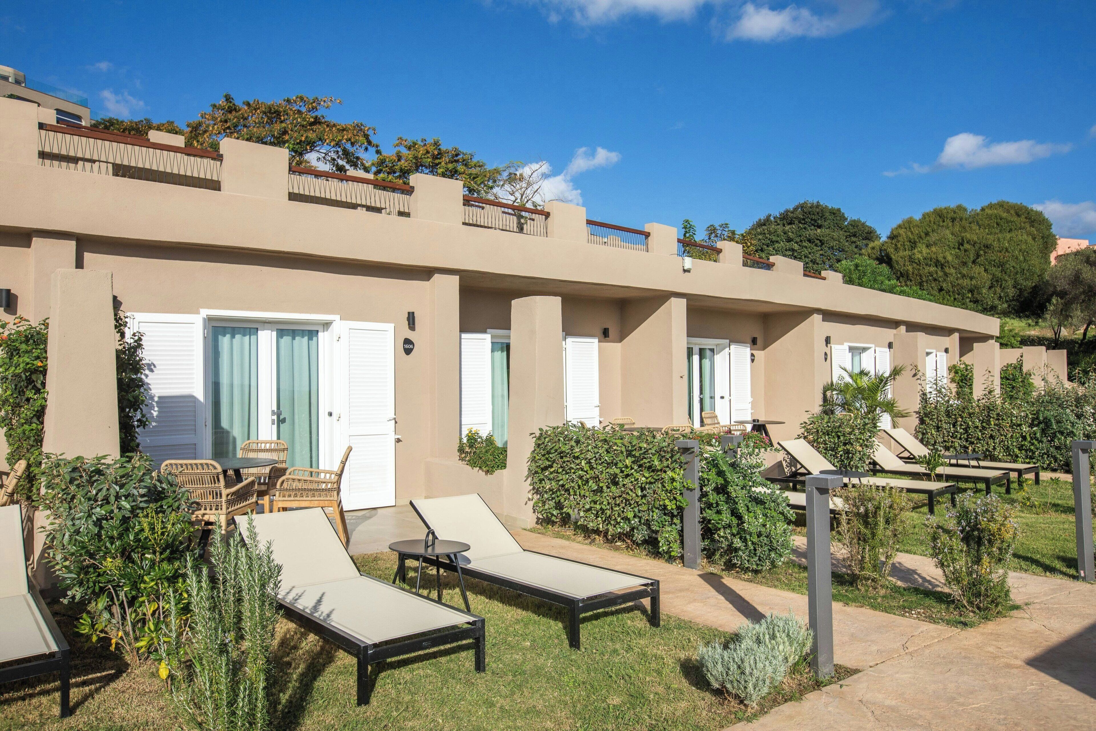A hotel with outdoor seating, a pool area, and a garden.