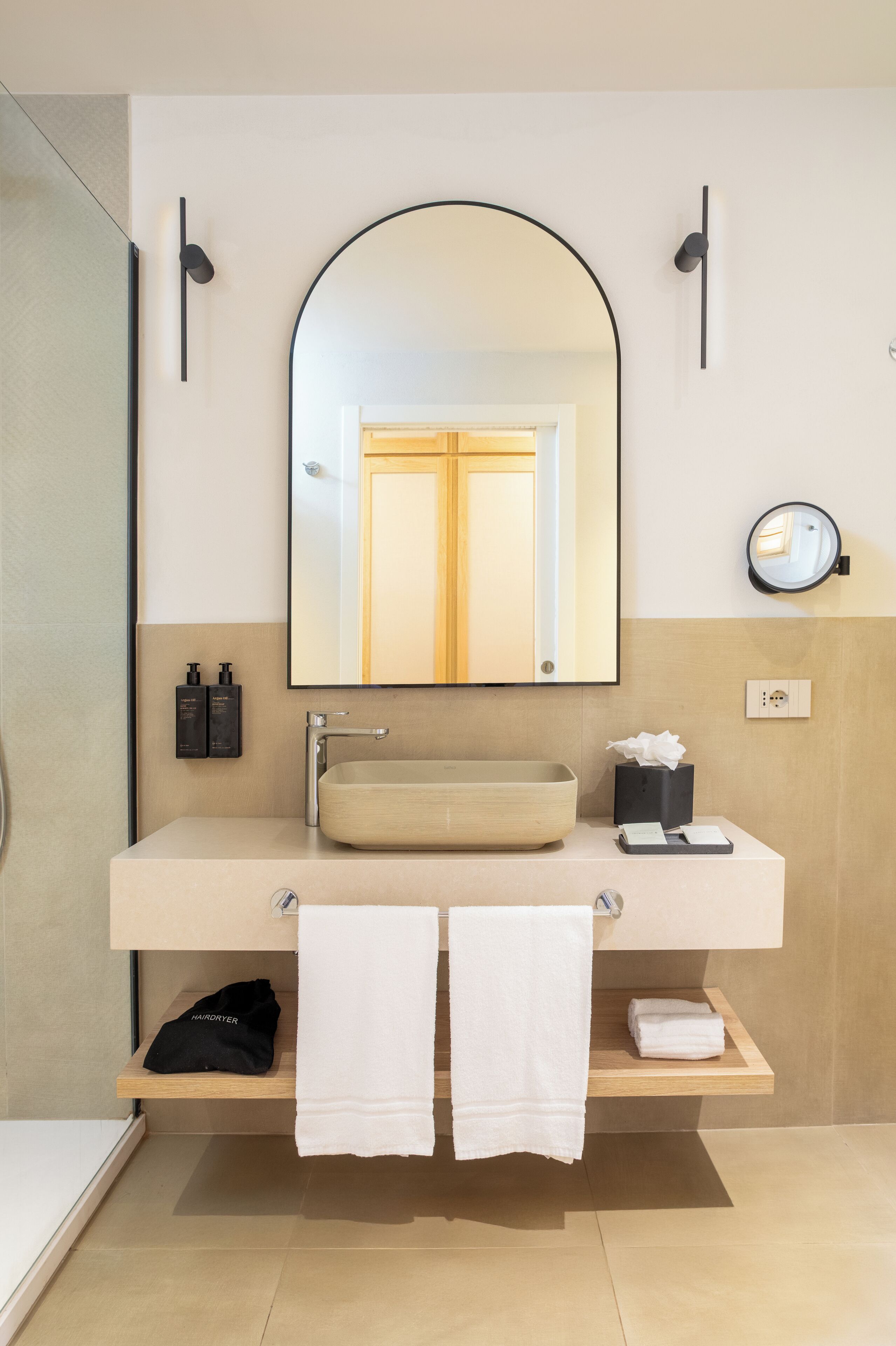 A modern bathroom with a large mirror, a sink, and a towel rack.