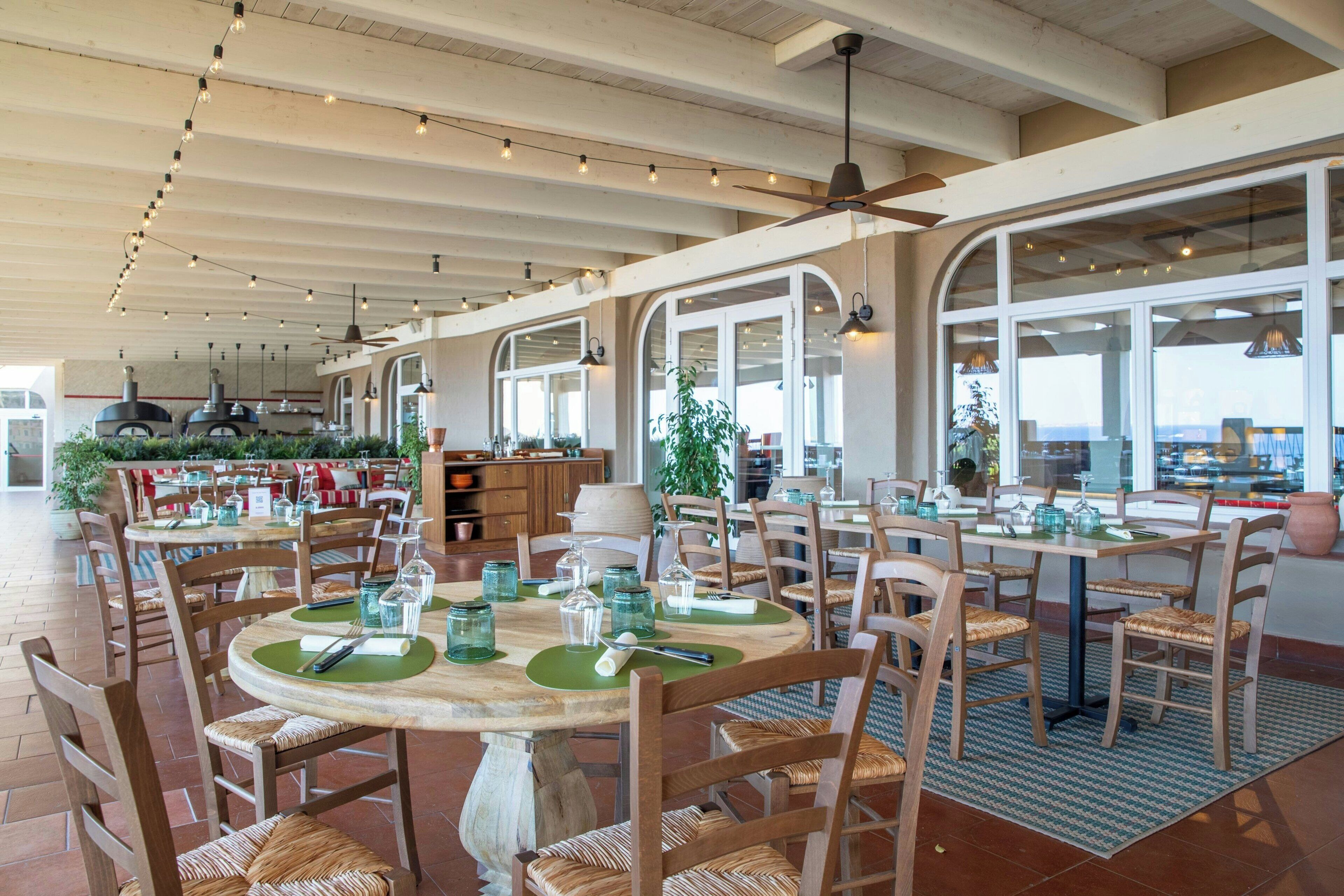 Un restaurant avec une terrasse, des tables et des chaises en bois, et une vue sur le paysage urbain.