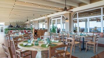 Un restaurant avec une terrasse, des tables et des chaises en bois, et une vue sur le paysage urbain.