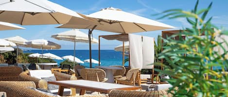 Outdoor seating with umbrellas, wicker furniture, and a view of the sea.