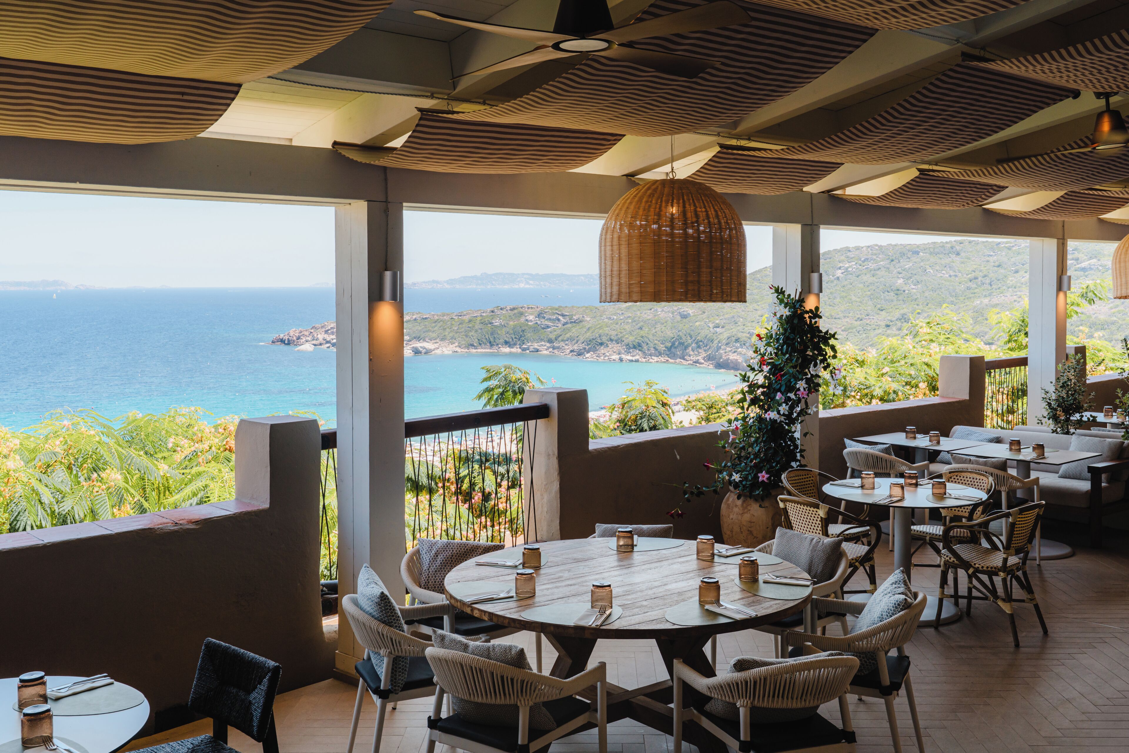An outdoor dining area with tables and chairs, overlooking a coastal landscape.