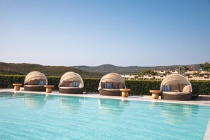 A poolside area with four covered seating areas and a view of the surrounding landscape.