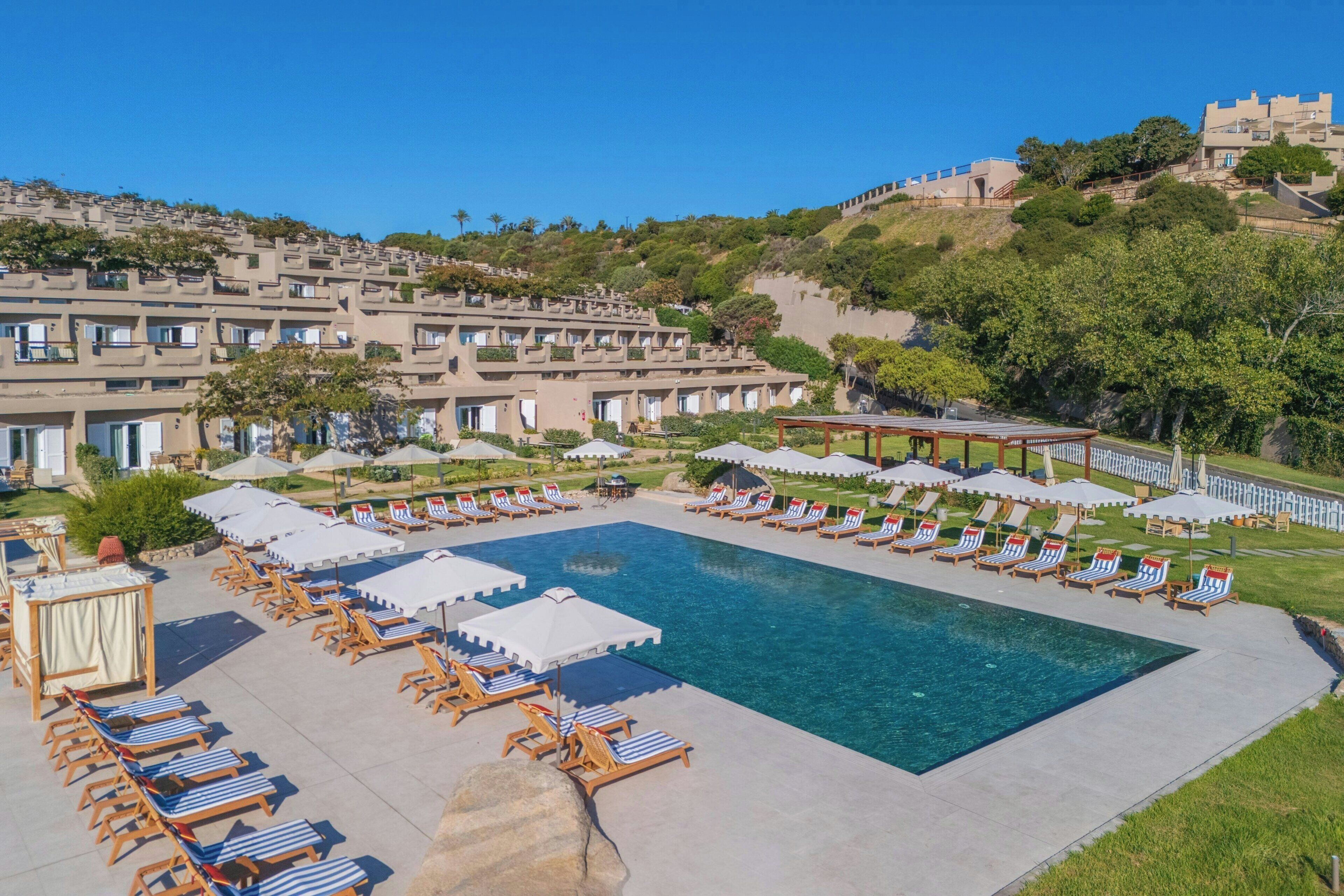 Un resort con una grande piscina circondata da lettini e ombrelloni.