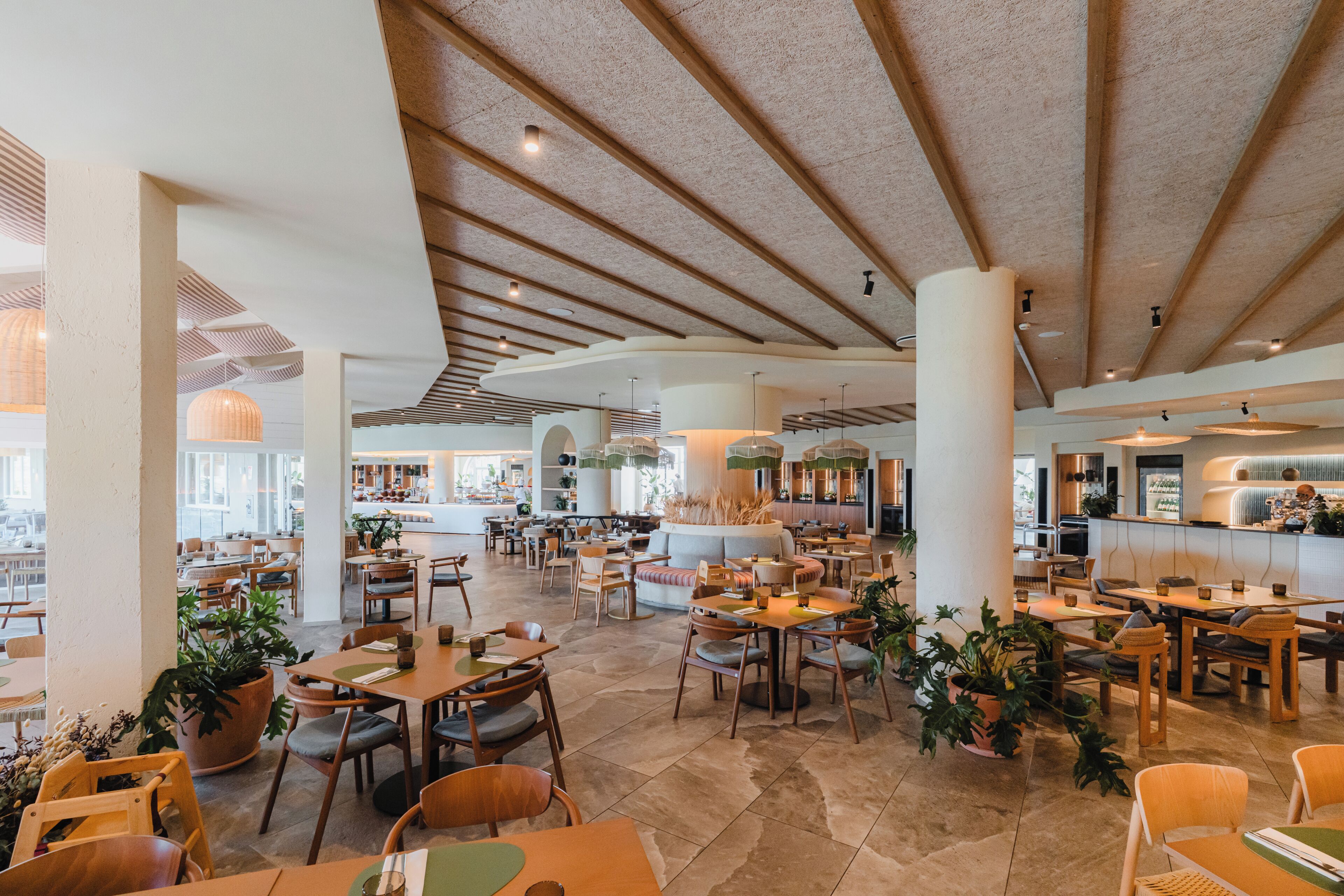 A spacious indoor dining area with multiple seating arrangements, including tables and chairs, and a central feature that appears to be a bar or counter.
