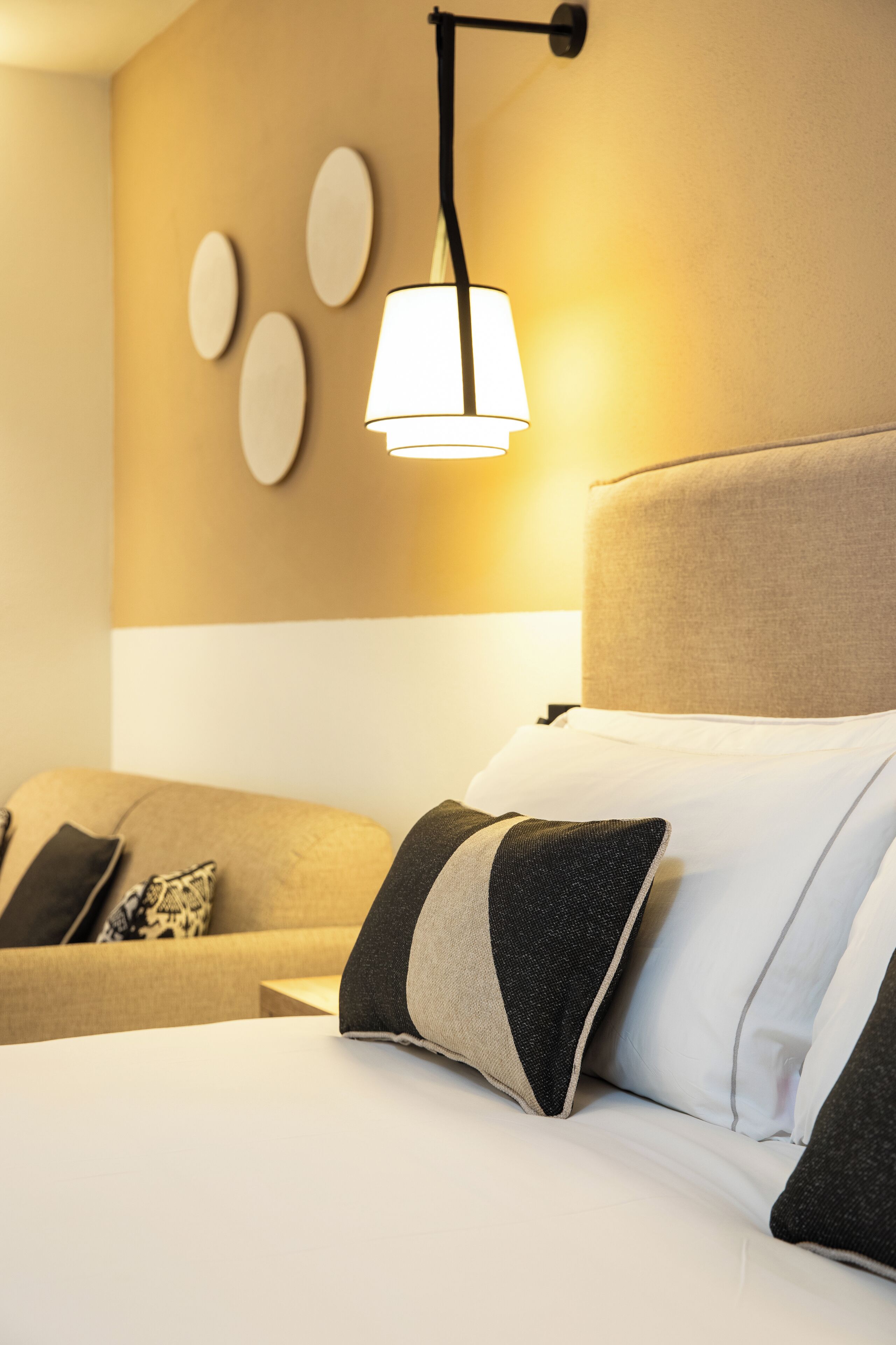 Ein Hotelzimmer mit Bett, Nachttisch, Lampe und einer Wand mit dekorativen Tellern.