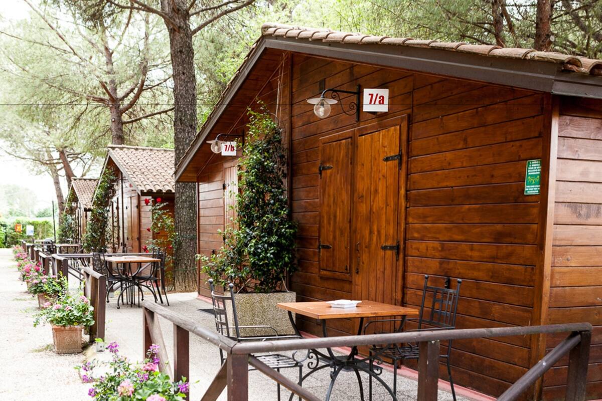 A row of wooden cabins with outdoor seating, each marked with a number sign.