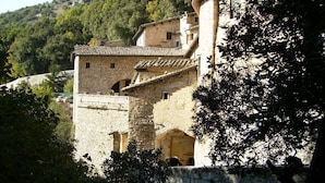 A stone building with a tiled roof, surrounded by trees and hills. - Green Village Assisi (Assisi)