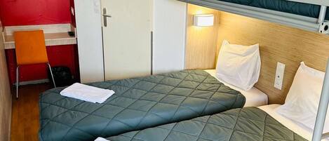A compact room with bunk beds, a small desk, and a chair.