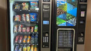 Two beverage vending machines with a variety of drink options and a digital screen displaying a coffee advertisement. - Première Classe Dunkerque - Saint-Pol-Sur-Mer (Dunkirk)