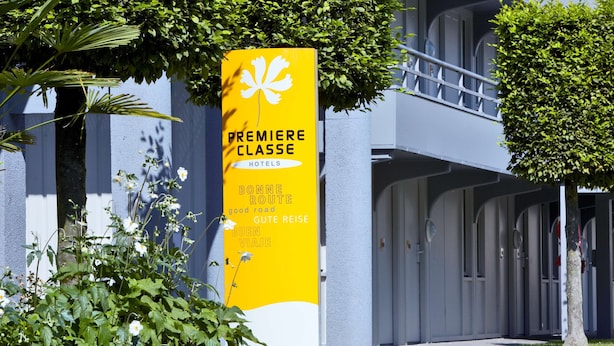 Un panneau jaune sur lequel on peut lire « HÔTELS DE PREMIÈRE CLASSE » et « BONNE ROUTE », indiquant la présence d’un hôtel appelé « Bonne Route ».